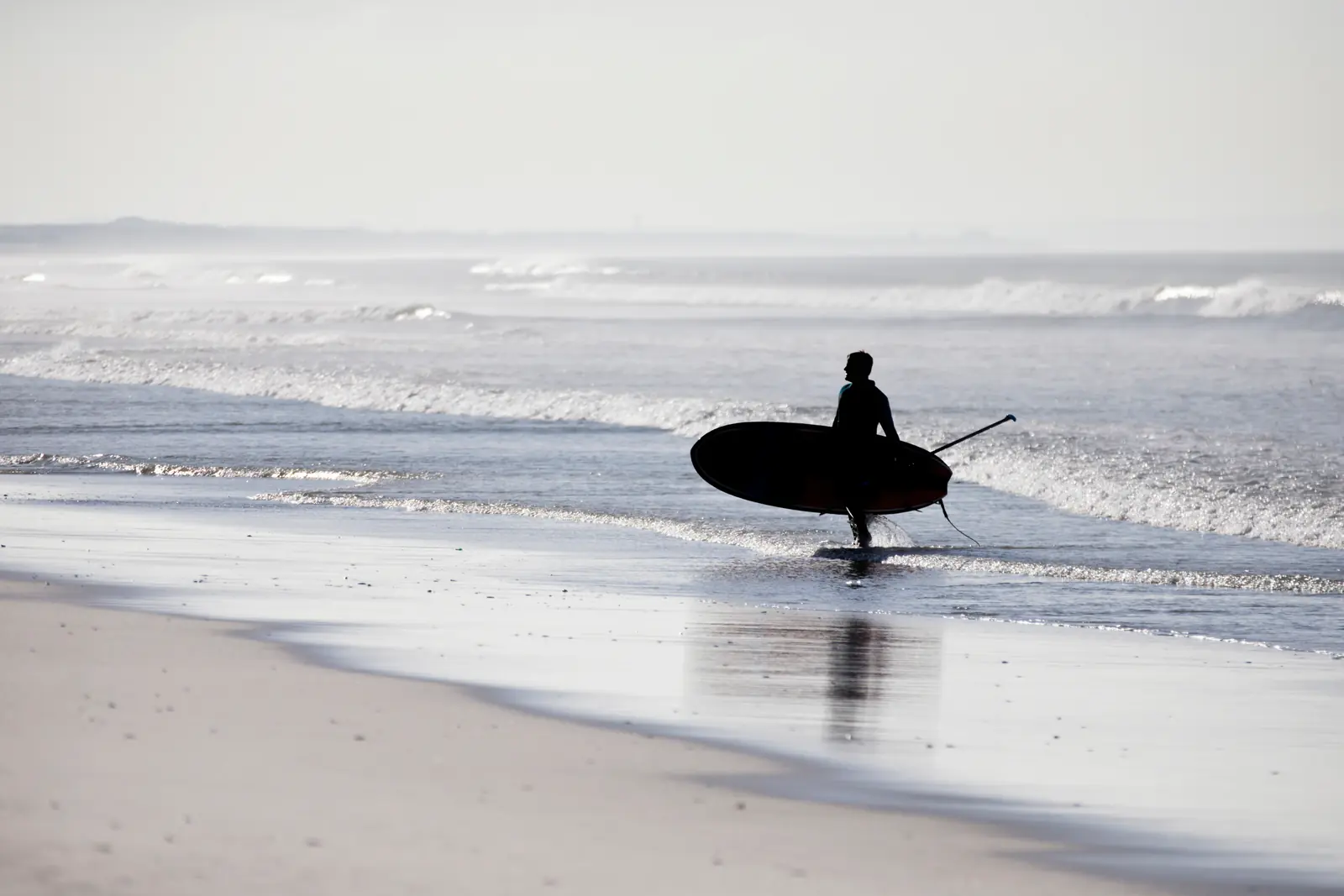 A paddleboarder returning to shore in evening light