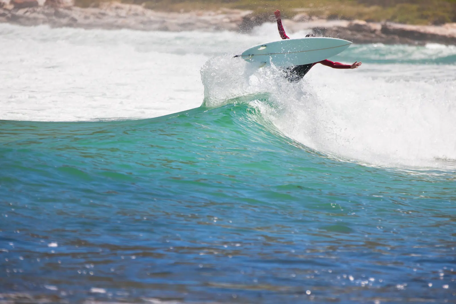 A surfer carving across a sunlit wave