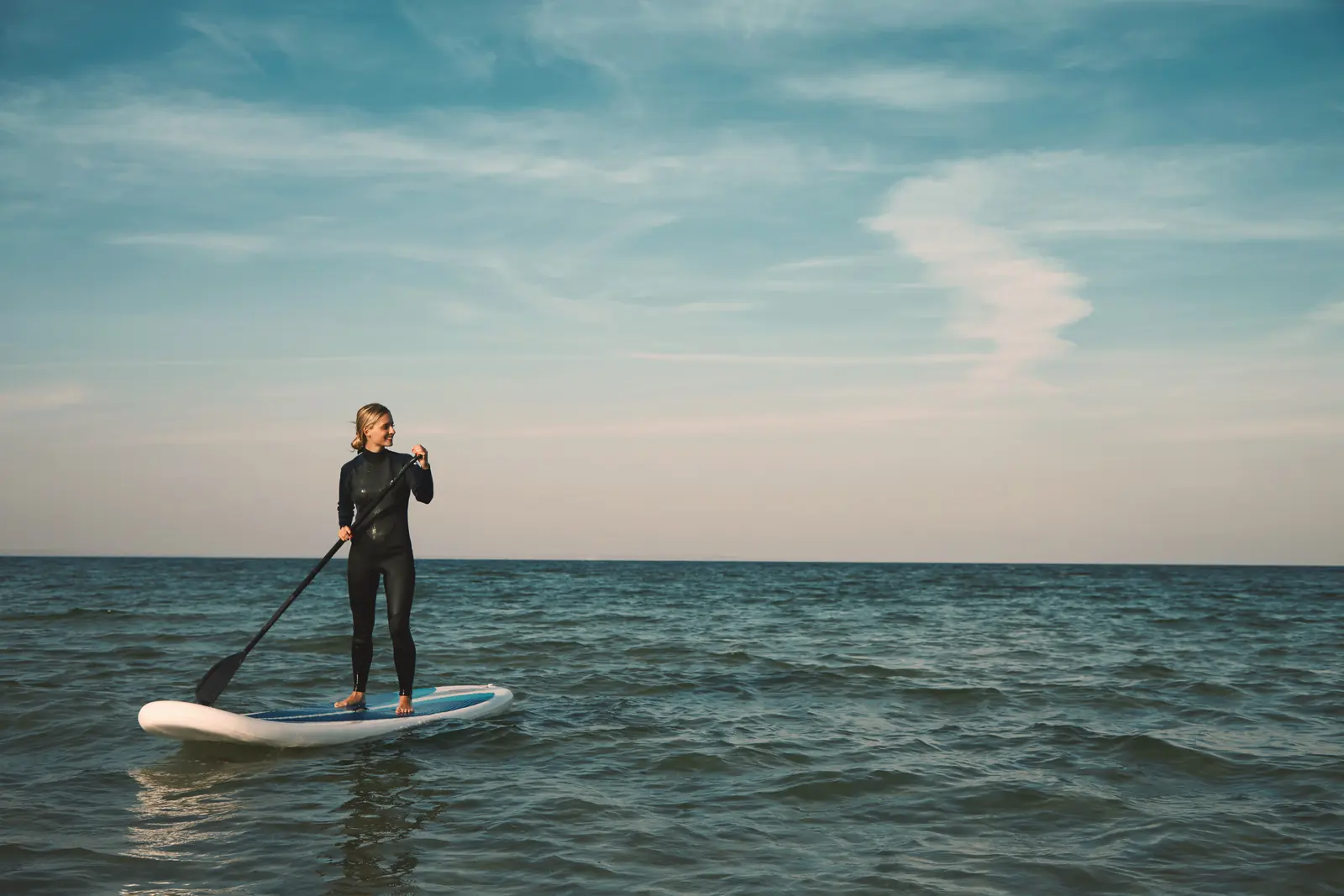 A paddleboarder standing on open ocean water