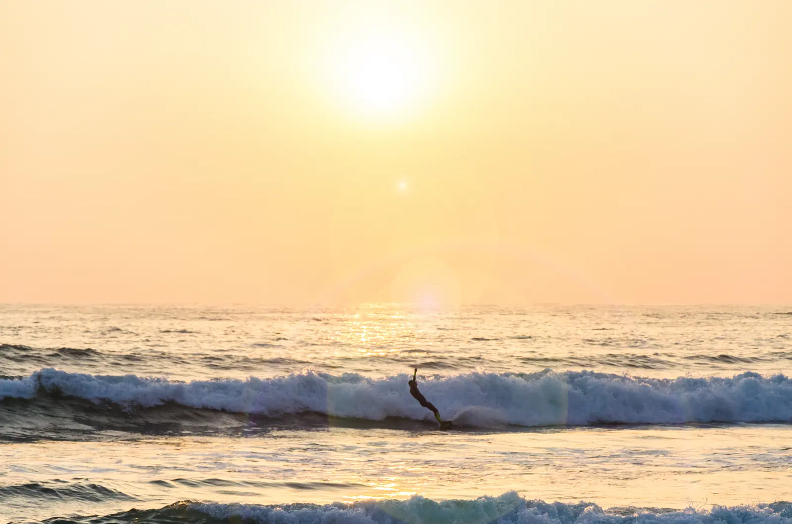 A surfer riding a wave in warm evening light