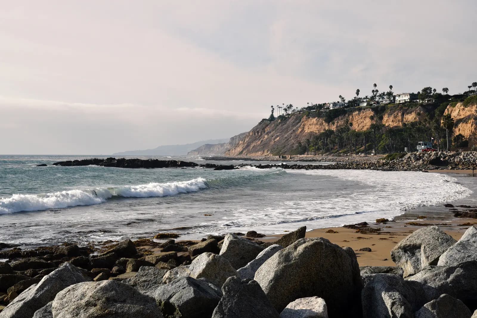 A rocky South Bay beach beneath low coastal bluffs