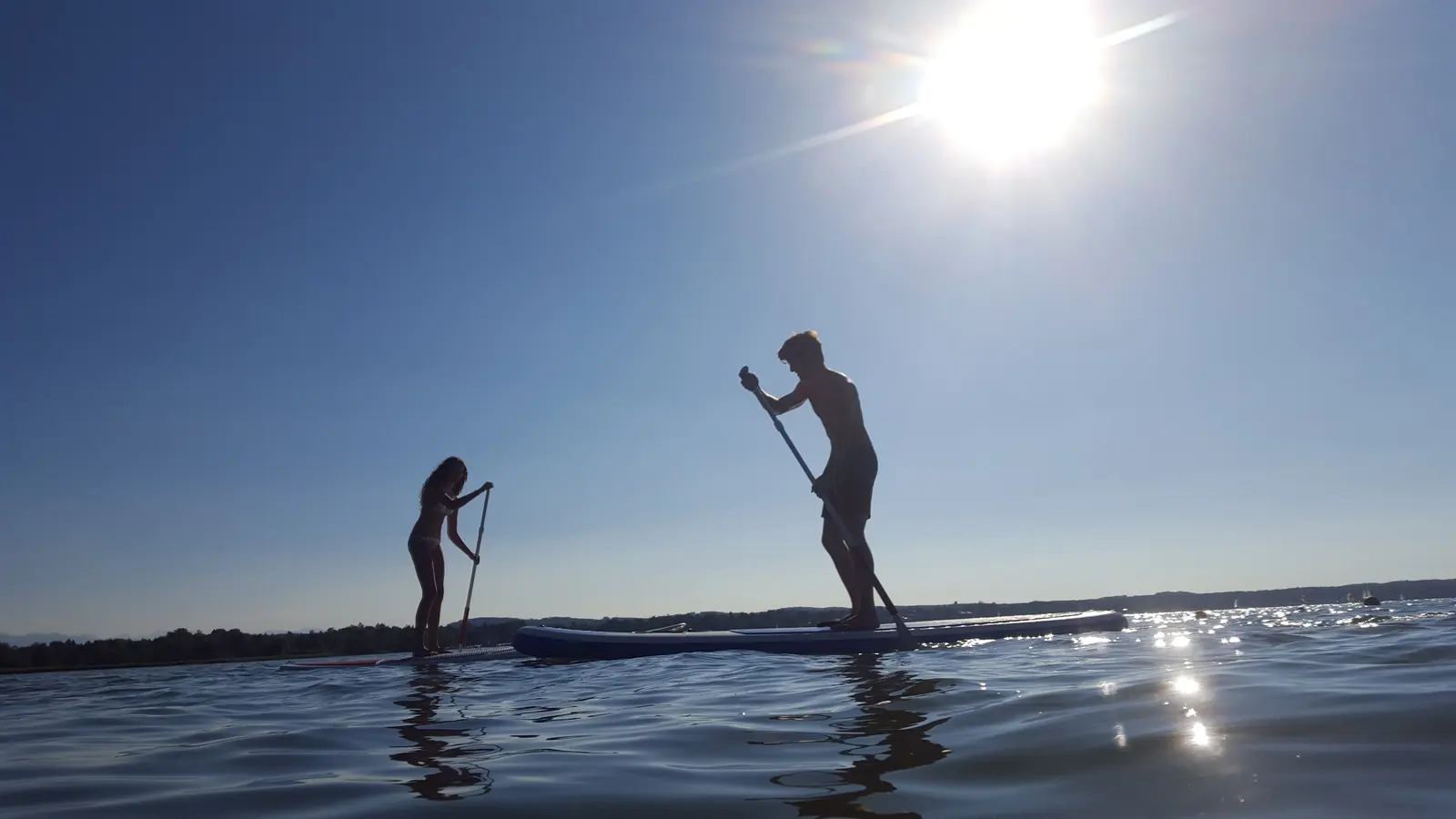 Two paddleboarders silhouetted against open coastal water