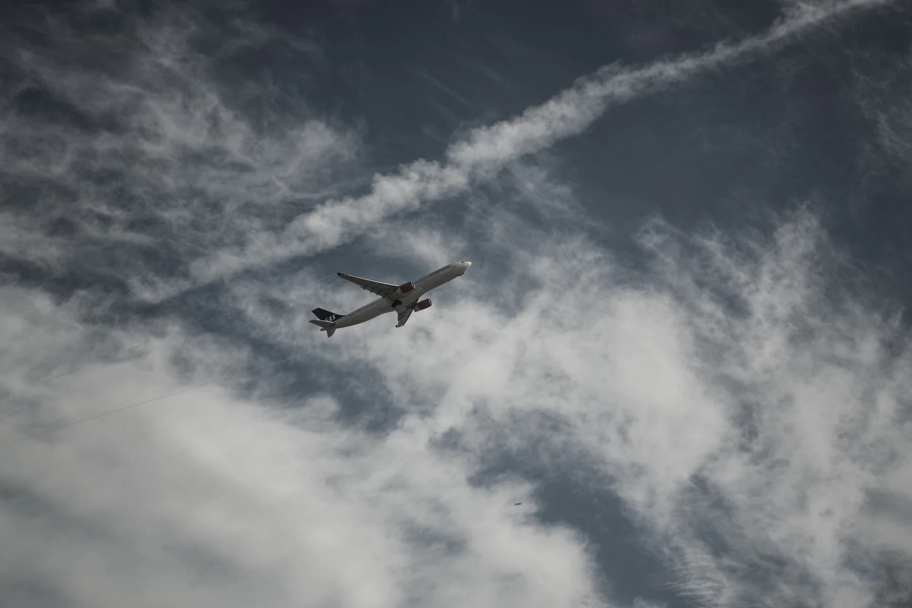 An aircraft crossing a cloud-streaked coastal sky