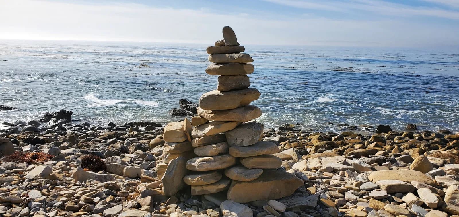 A hand-built stone cairn beside the rocky Pacific shoreline