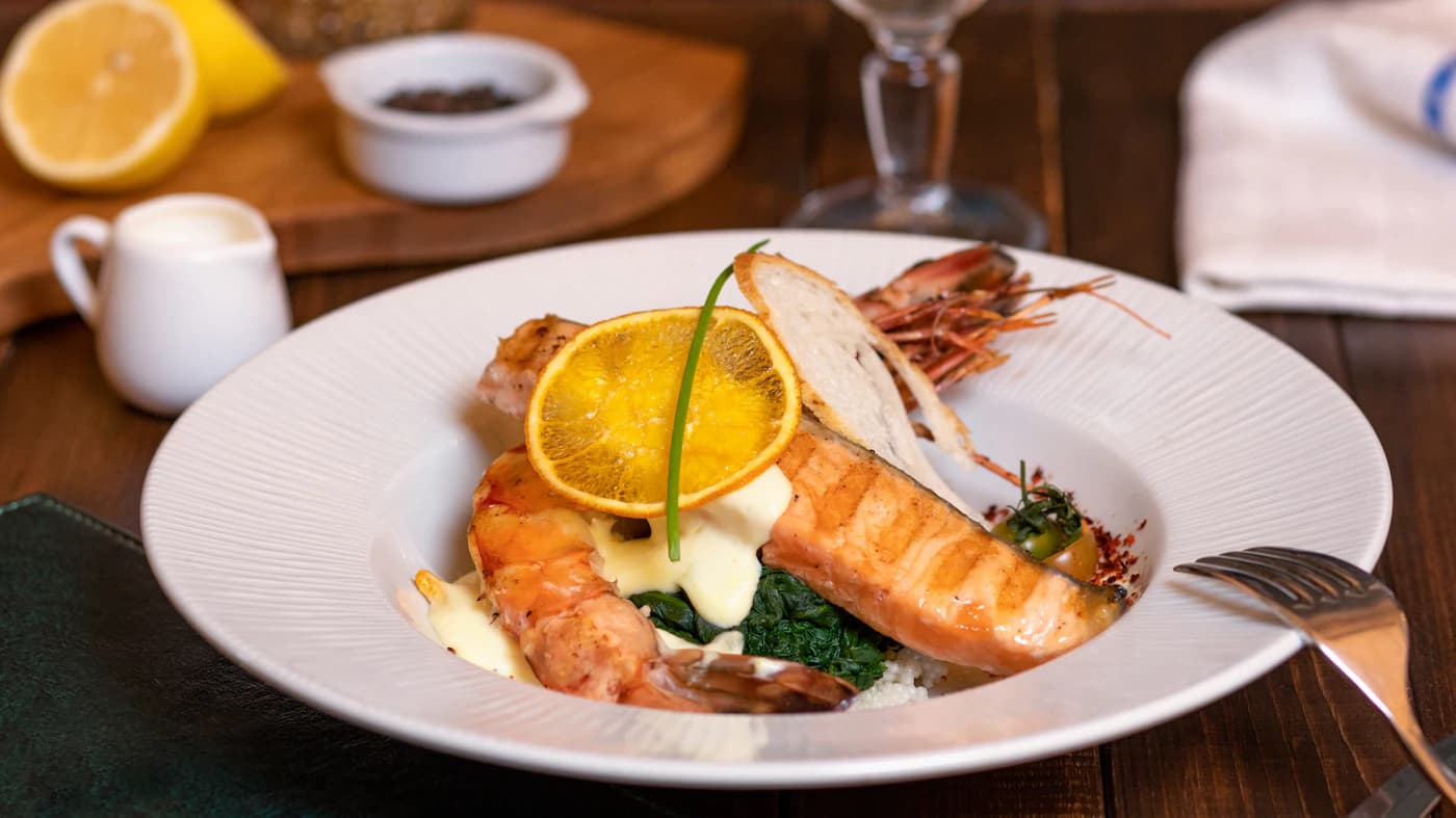 A plated seafood dinner with salmon, shellfish, and lemon