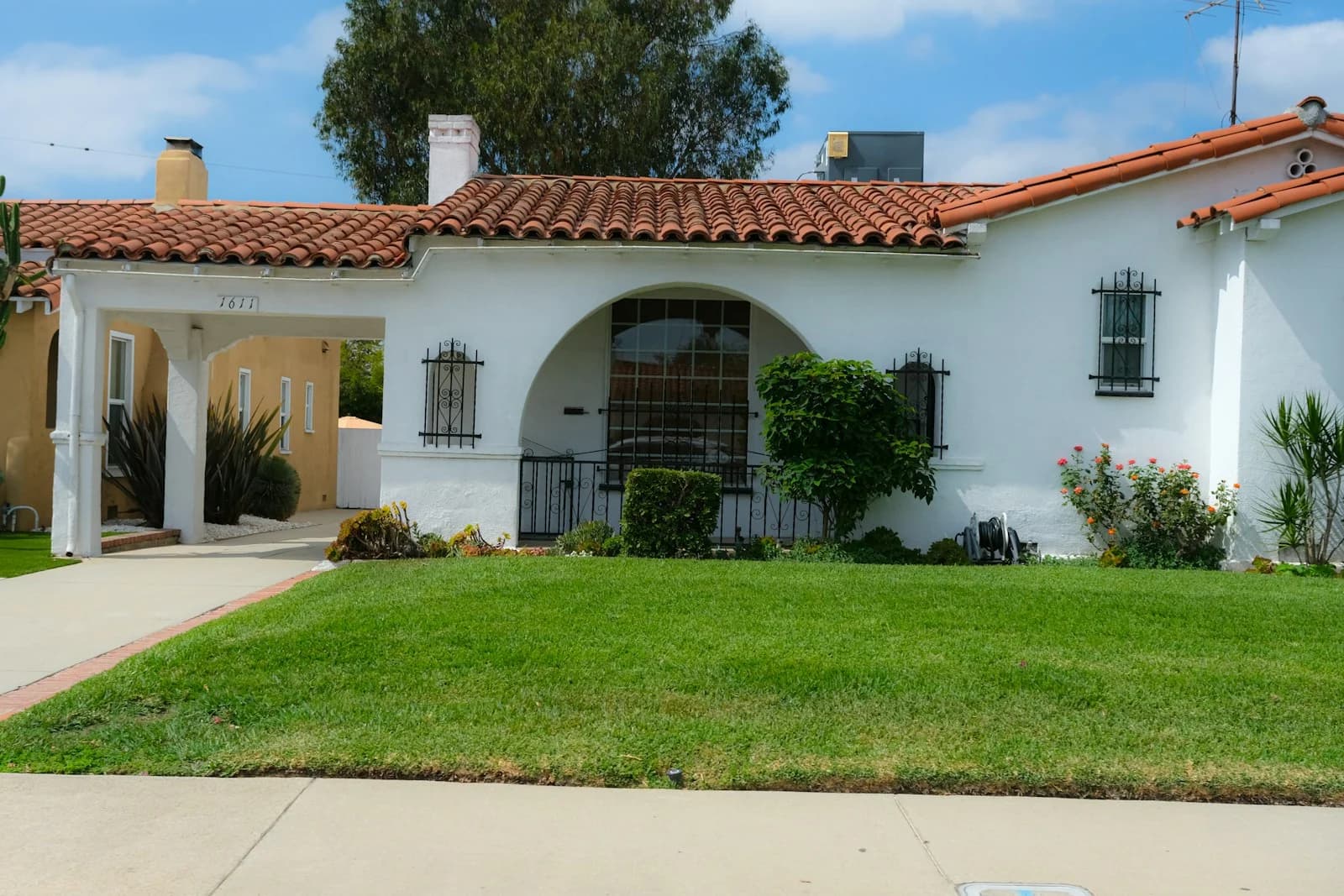 A low white Spanish bungalow with a red clay tile roof