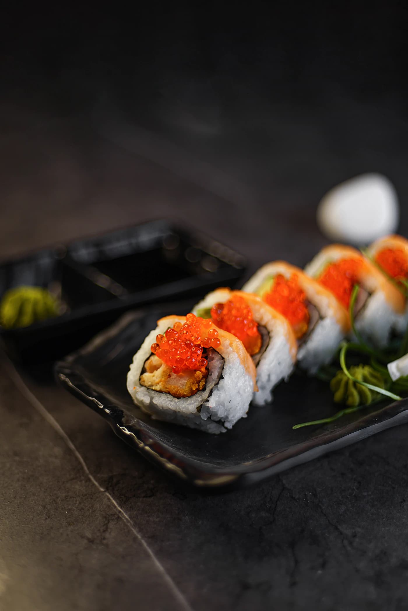 Fresh sushi rolls presented on a dark ceramic plate