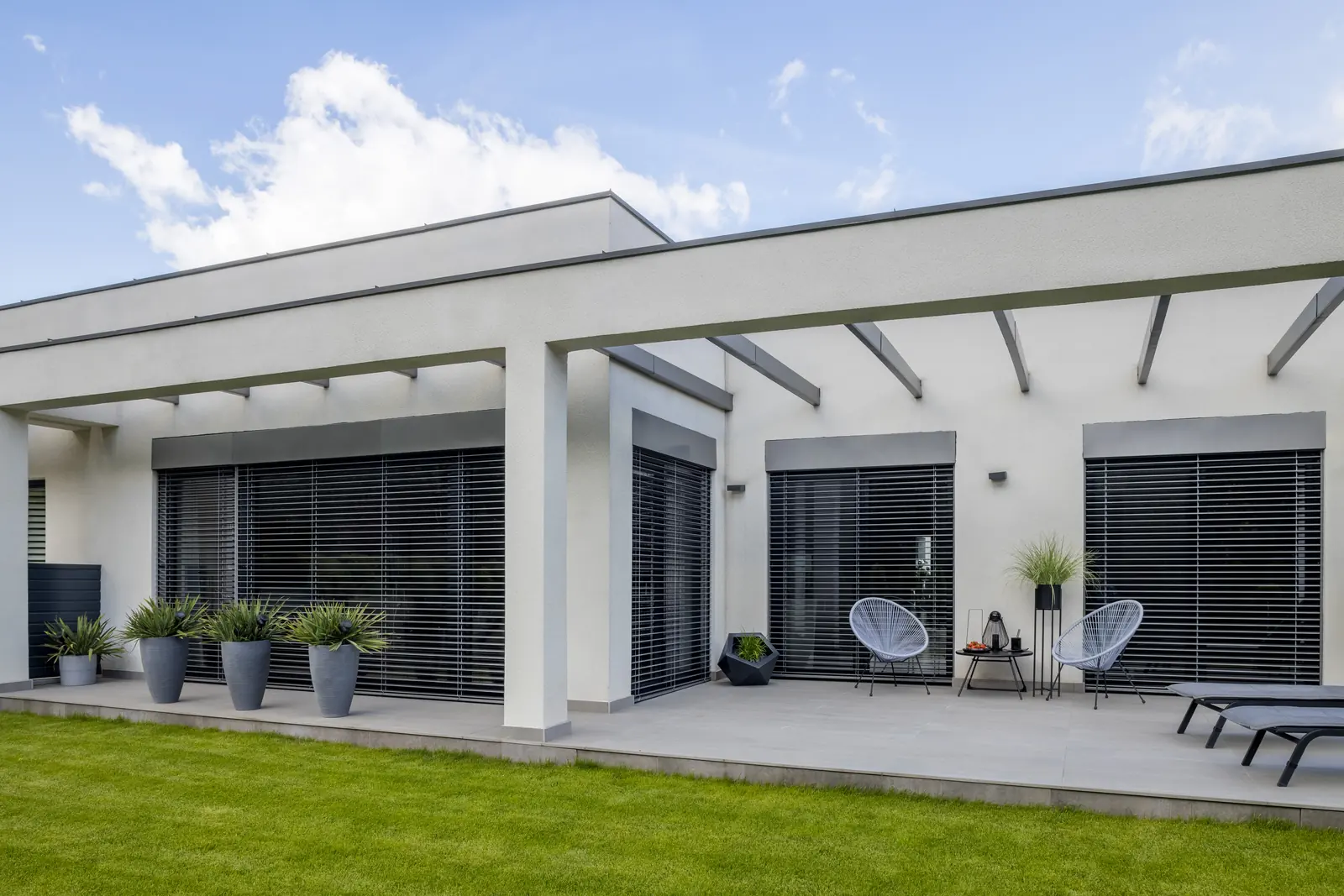A dark-accented suburban home with a broad shaded patio