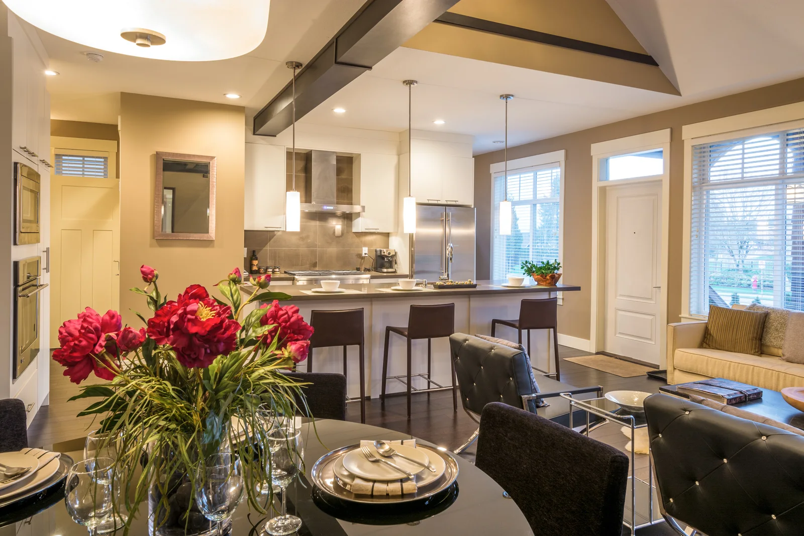 An upscale open kitchen and dining room with warm wood beams