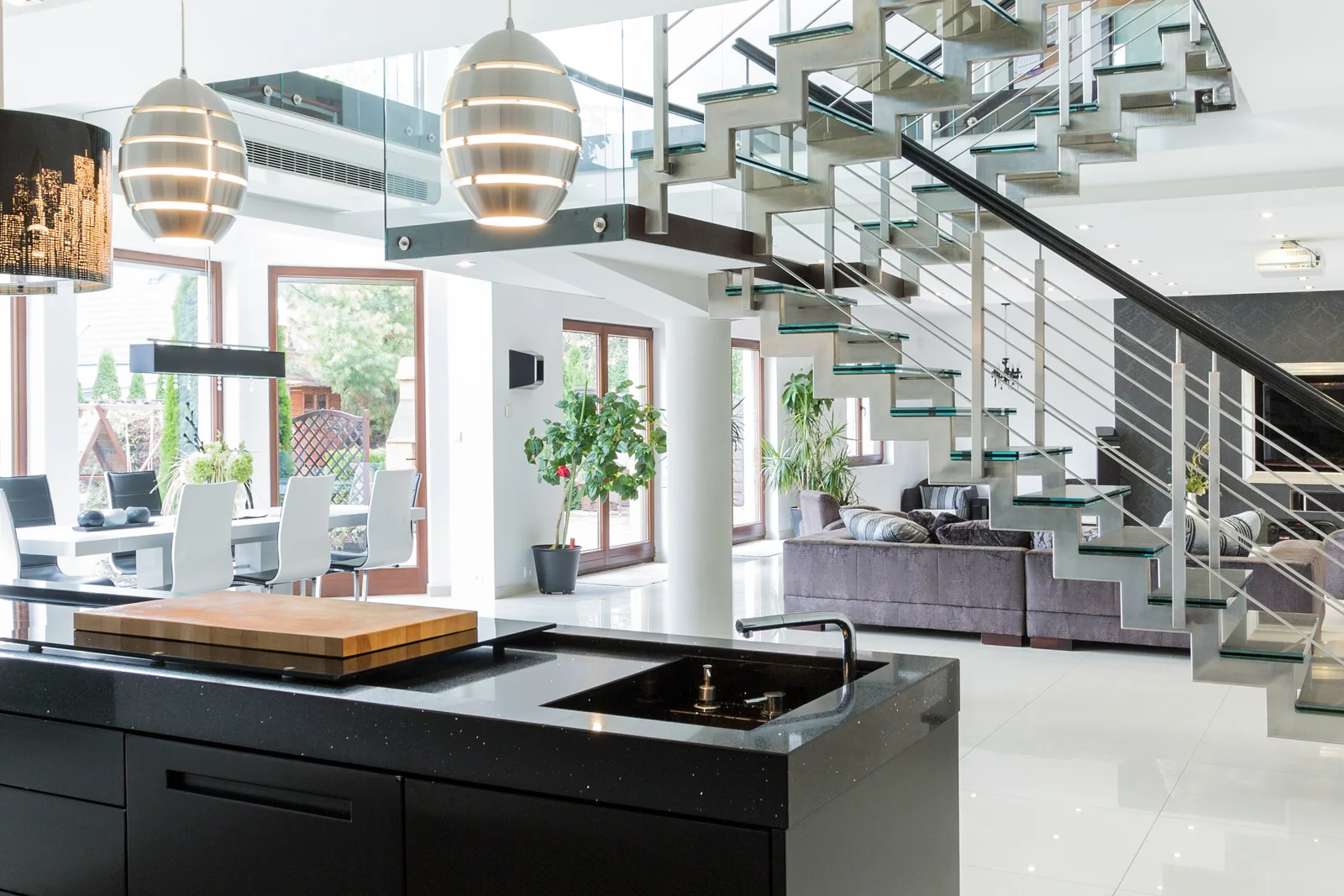 A panoramic luxury-estate interior with an open kitchen and sculptural staircase